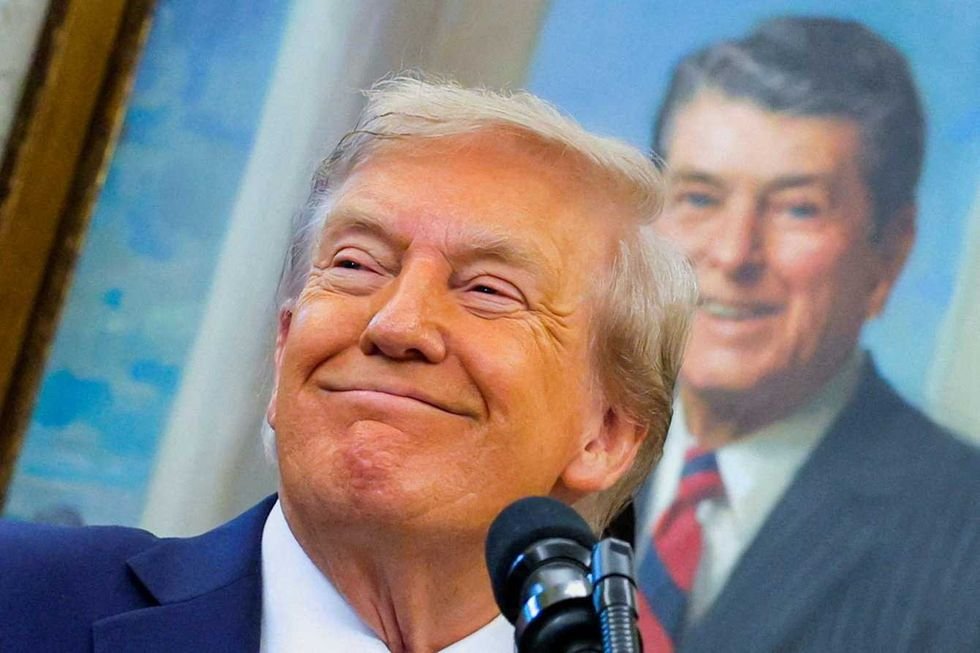 u s president donald trump in front of a painting of former u s president ronald reagan smiles during an event to announce t